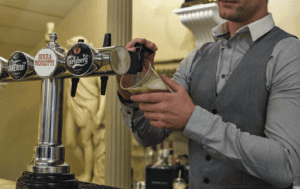 Picture of a smartly dressed man pulling a pint.