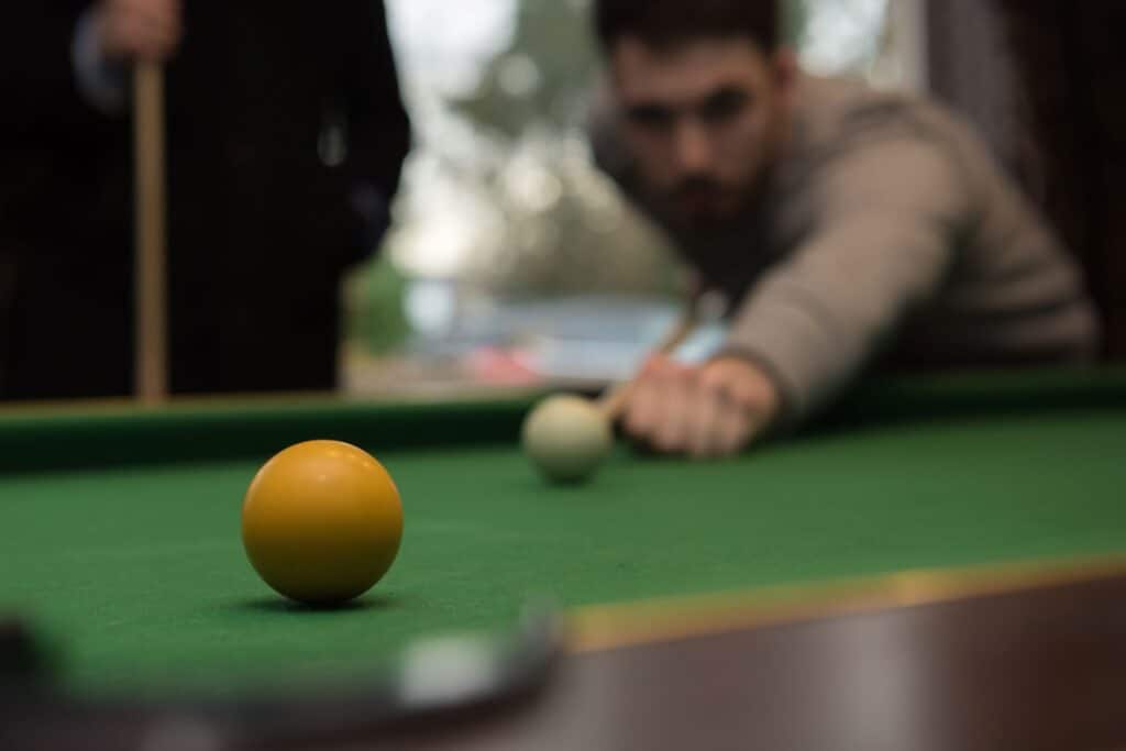 A young man taking a pool shot