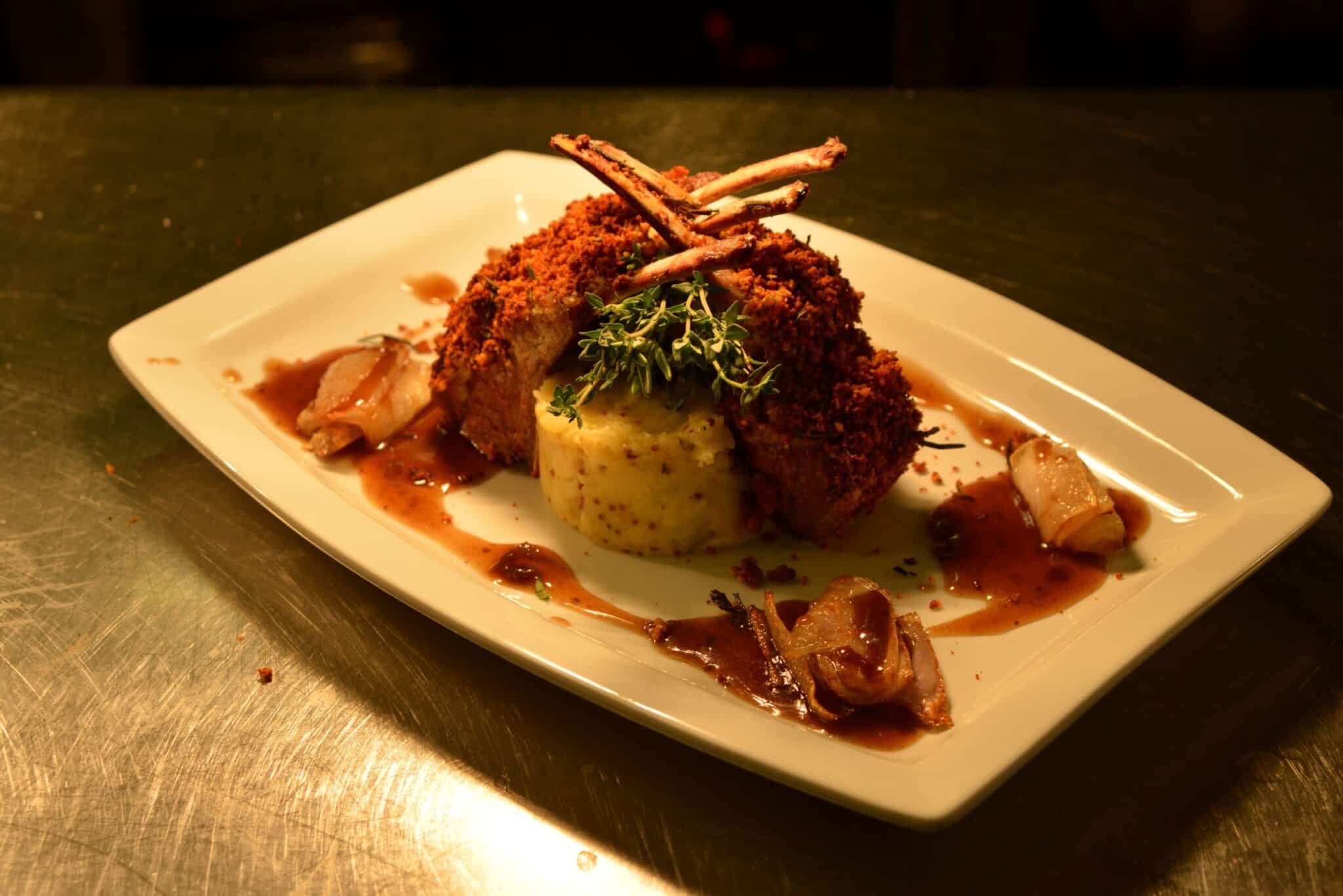 A plate of lamb rack, on crushed potatoes and a jus.