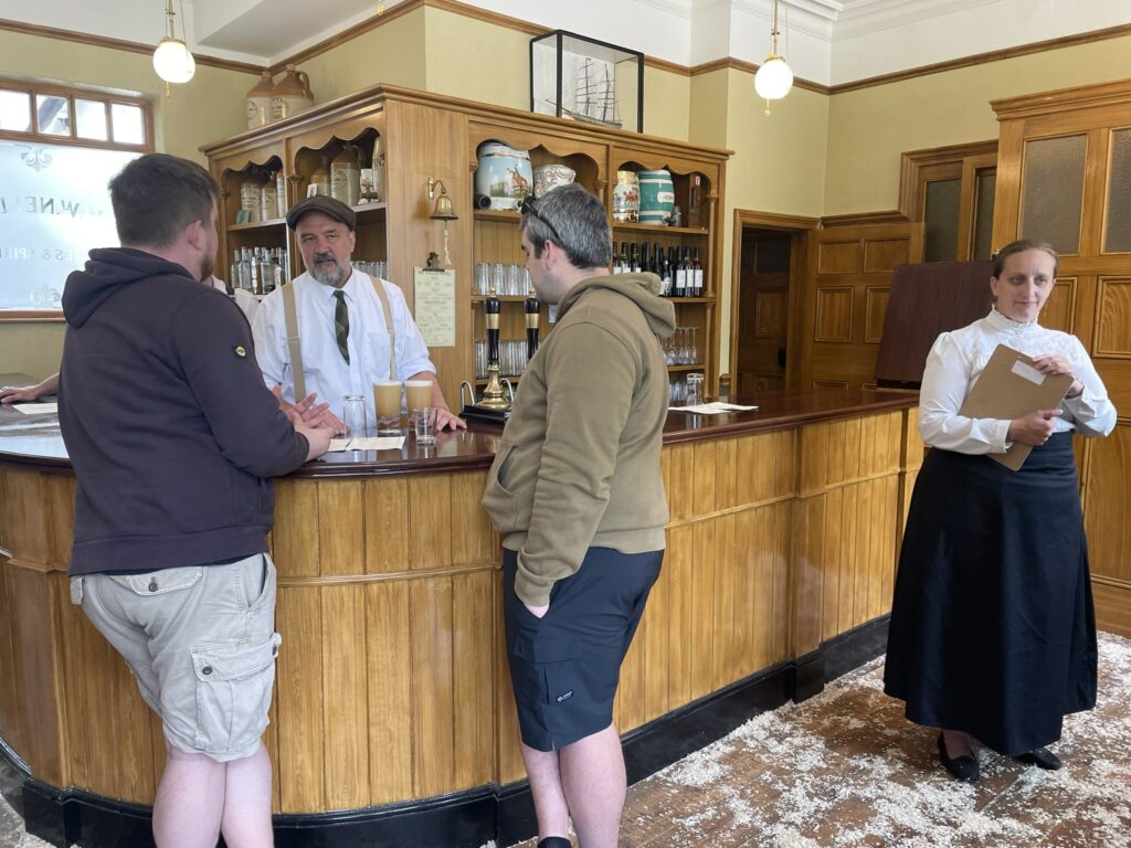 Inside the Vulcan - a bar with the staff in period costume serving two customers.