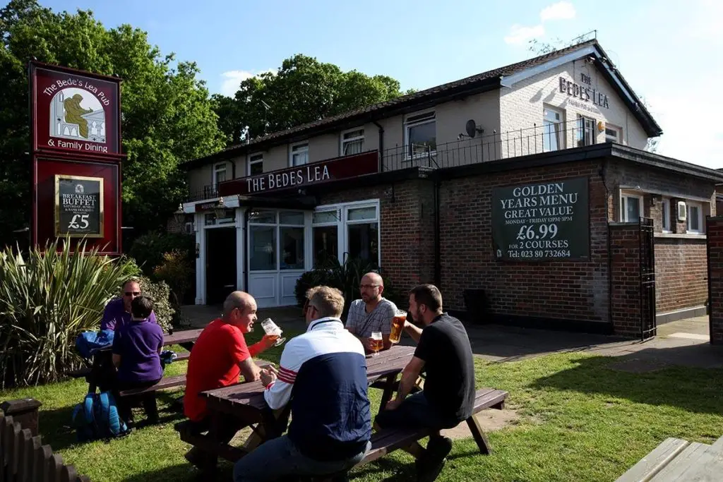 A picture of the Bede's Lea pub from the front, with customers enjoying a sunny pint or two.