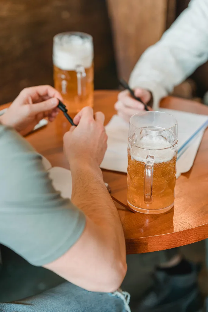 Two people have a conversation over a pint, whilst making notes.